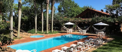 Una piscina al aire libre, sombrillas, sillones reclinables de piscina