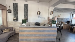 Una moderna zona de recepción con una pared de piedra, un letrero que dice 'Welcome' y un mostrador con una máquina de café.
