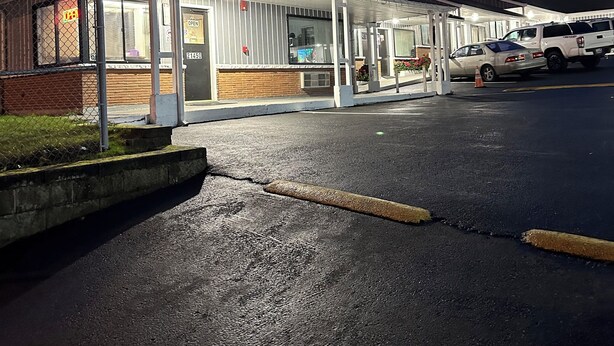 Un motel doté d’un parking couvert et d’un bâtiment sur lequel est affiché un panneau indiquant si des chambres sont disponibles.