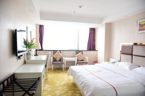 A hotel room with a bed, a desk with a chair, a TV, and a window with curtains. - Jiaxing ShiMao Inn (Jiaxing)