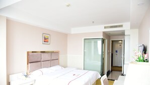 A hotel room with a bed, bedside table, lamp, and a door leading to a bathroom. - Jiaxing ShiMao Inn (Jiaxing)