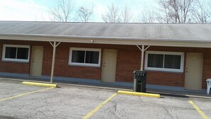 A single-story brick building with a flat roof, two windows on the front, and a door. There is a yellow curb in the parking lot. - Motel Plaza (Vermilion)