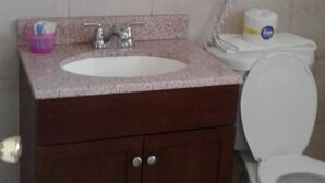 A bathroom with a white sink, dark wooden vanity, a mirror, a hairdryer, and a toilet. - Motel Plaza (Vermilion)
