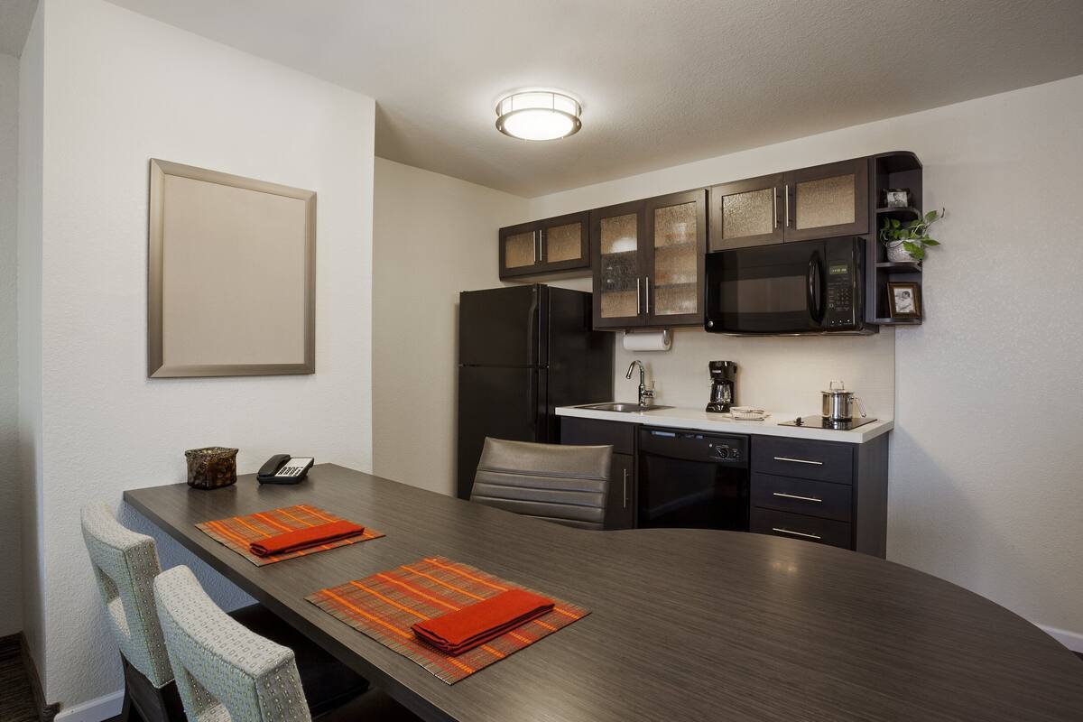 A compact kitchen with dark cabinetry, a microwave, and a refrigerator.