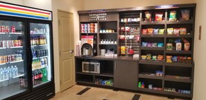A vending area with a microwave, a free cup of joe, and various snacks and drinks. - Candlewood Suites Plano North by IHG (Plano)