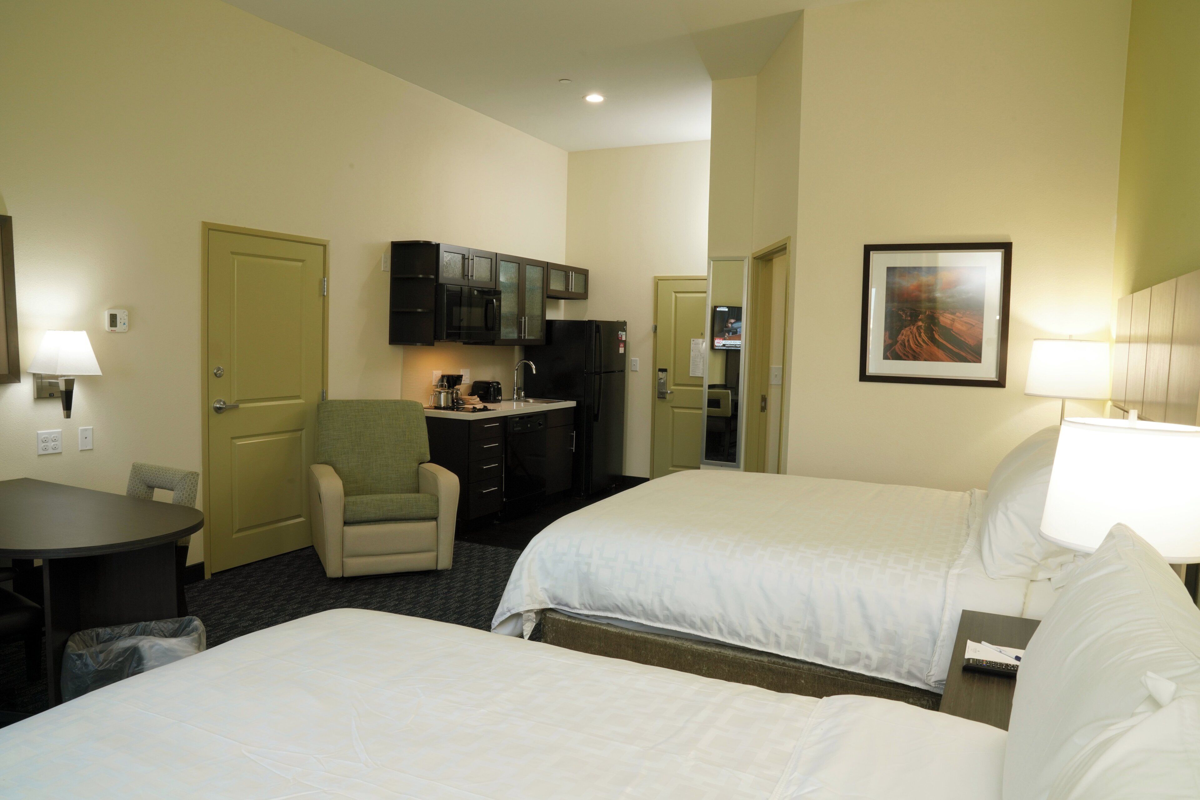 A hotel room with two beds, a desk with a chair, a microwave, and a television.