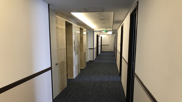 A hotel hallway with carpeted floors, doors on both sides, and a ceiling light fixture. - Toyoko Inn Ulaanbaatar (Ulaanbaatar)