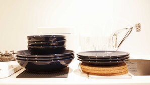 Una encimera de cocina con platos negros apilados, un electrodoméstico blanco y un grifo de acero inoxidable.