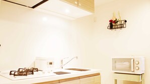 Una cocina con estufa a gas, lavamanos y microondas sobre un mueble.