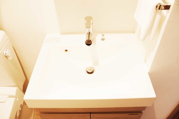 Un baño con lavamanos blanco, inodoro y espejo.