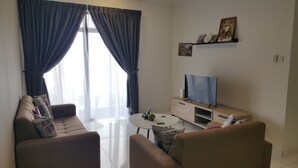 Ein Wohnzimmer mit Sofa, Couchtisch, Fernseher und Vorhängen.