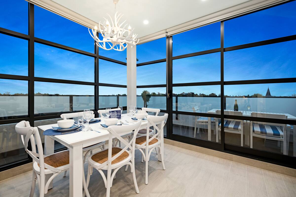 A dining area with a table set for four, large windows, and a chandelier.