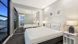 Een moderne hotelkamer met een groot bed, nachtkastjes, een spiegel en kunst aan de muur.