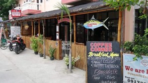 Ein Restaurant mit einer Schautafel, die Frühstücksangebote wie 'Pork Tapsilog' und 'Coconut Delight' auflistet.