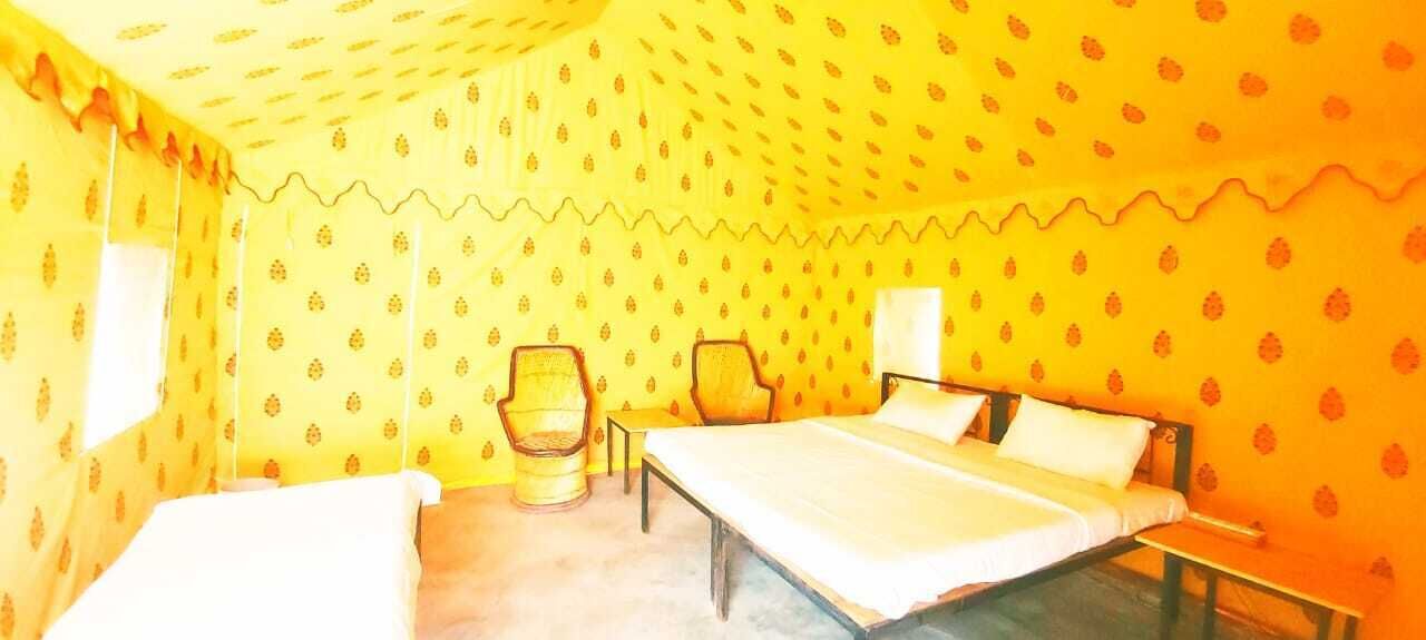 Quarto com cama, duas cadeiras, mesa de cabeceira e janela.