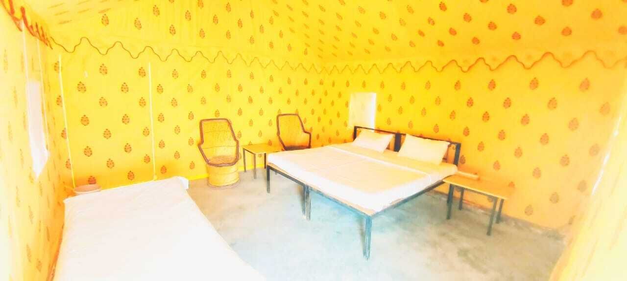 A room with a bed, two chairs, a small table, and a lamp.