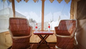 A tented room with two wicker chairs and a table, each with a bottle of water. - Desert Raasleela Camp (Jaisalmer)