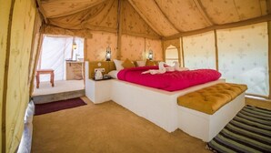 A tent-style room with a bed, bedside table, lamp, and a small seating area. - Desert Raasleela Camp (Jaisalmer)