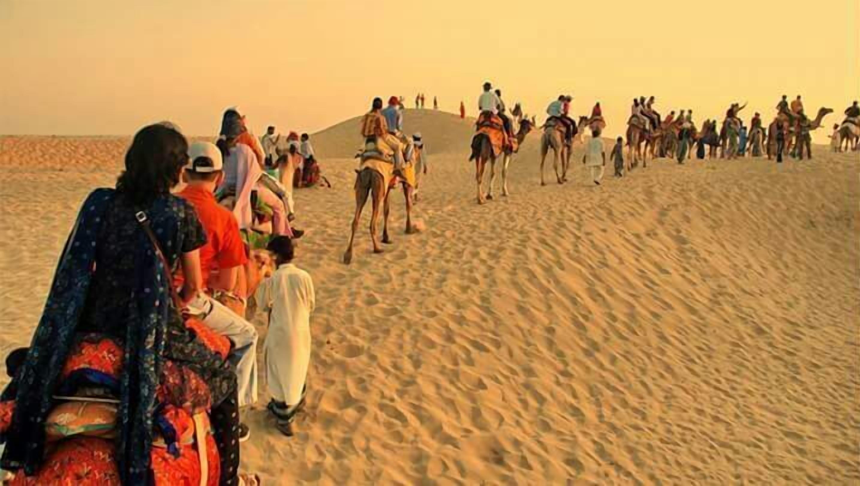 Un grupo de personas montando camellos en un paisaje desértico.