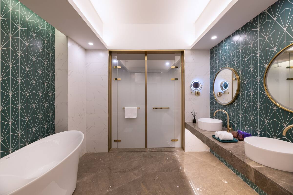 Ein modernes Badezimmer mit freistehender Badewanne, zwei Waschbecken und einem großen Spiegel.