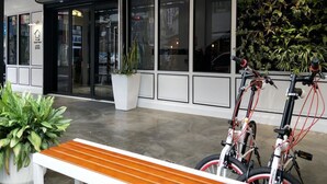 A modern building entrance with glass doors, a bench, and two bicycles parked outside. - Small Hotel (Luodong)
