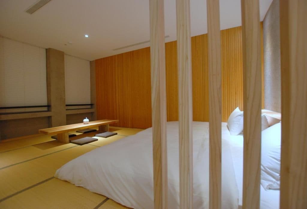 Een kamer met een bed, een bankje en een kleine tafel.