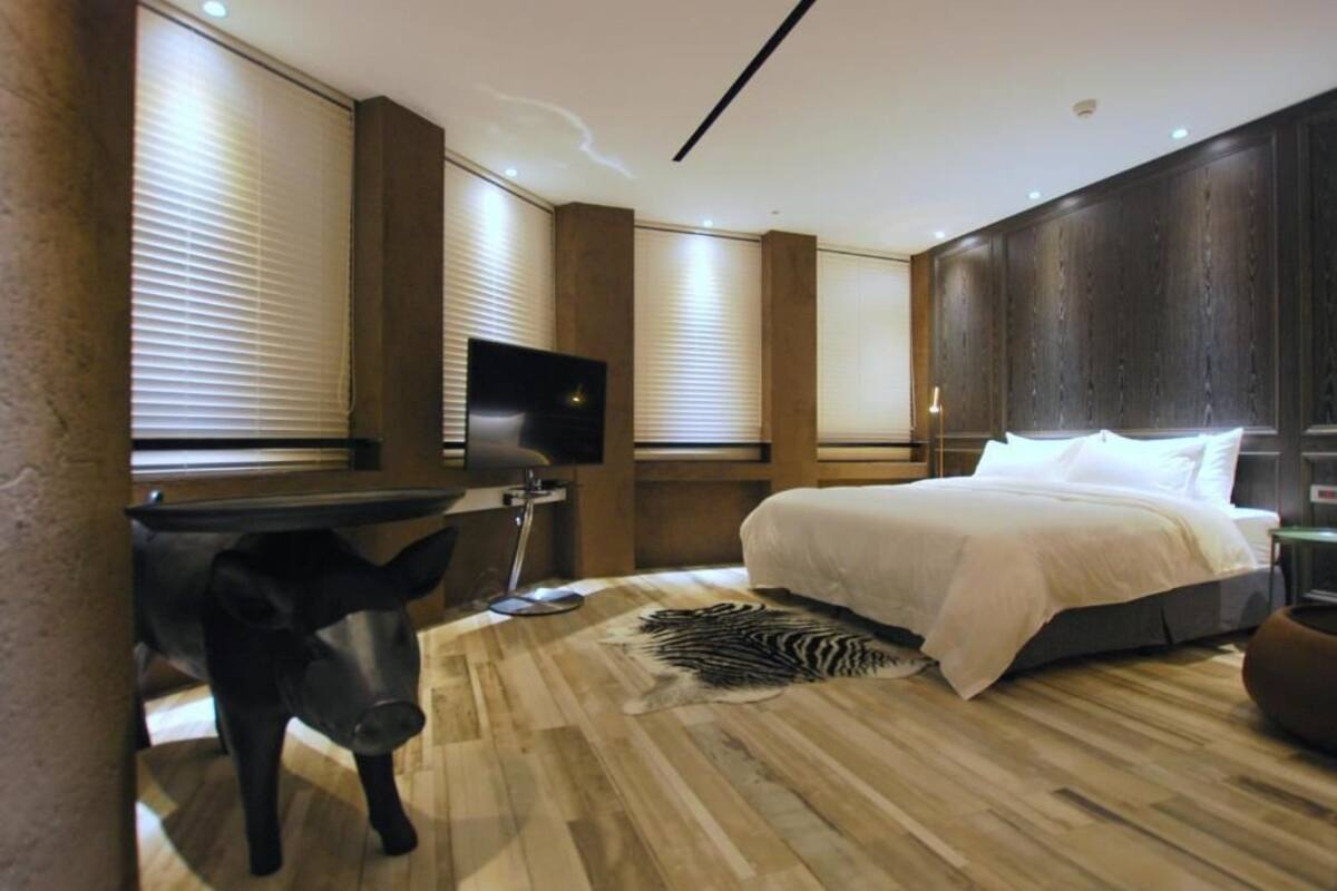 A modern bedroom with a large bed, a desk, and a television.