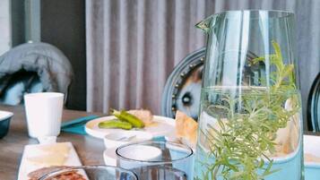 Una mesa con una jarrón de agua, dos vasos y un plato de comida.
