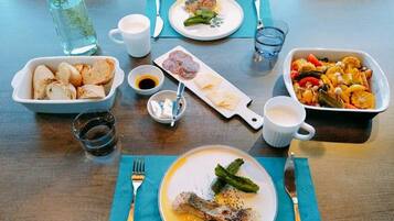 A dining table with various dishes, including a plate with a fish head, a bowl of vegetables, and a glass of water.