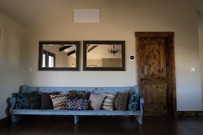 Una habitación con un sofá azul, dos espejos, una puerta de madera y una araña.