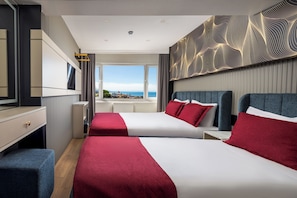 Ein Hotelzimmer mit zwei Betten, einem großen Fenster, einem Flachbildfernseher und einer dekorativen Wandverkleidung.