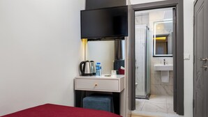 A hotel room with a bed, a desk with a kettle, a bottle of water, and a mirror. - Sultanahmet Nu Hotel (Istanbul)