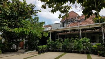A courtyard with potted plants, a building with a tiled roof, and a sign reading "La Nostalgia".