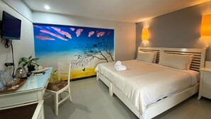 Une chambre d’hôtel équipée d’un lit, d’un bureau, d’une chaise, d’un téléviseur et d’une décoration murale.