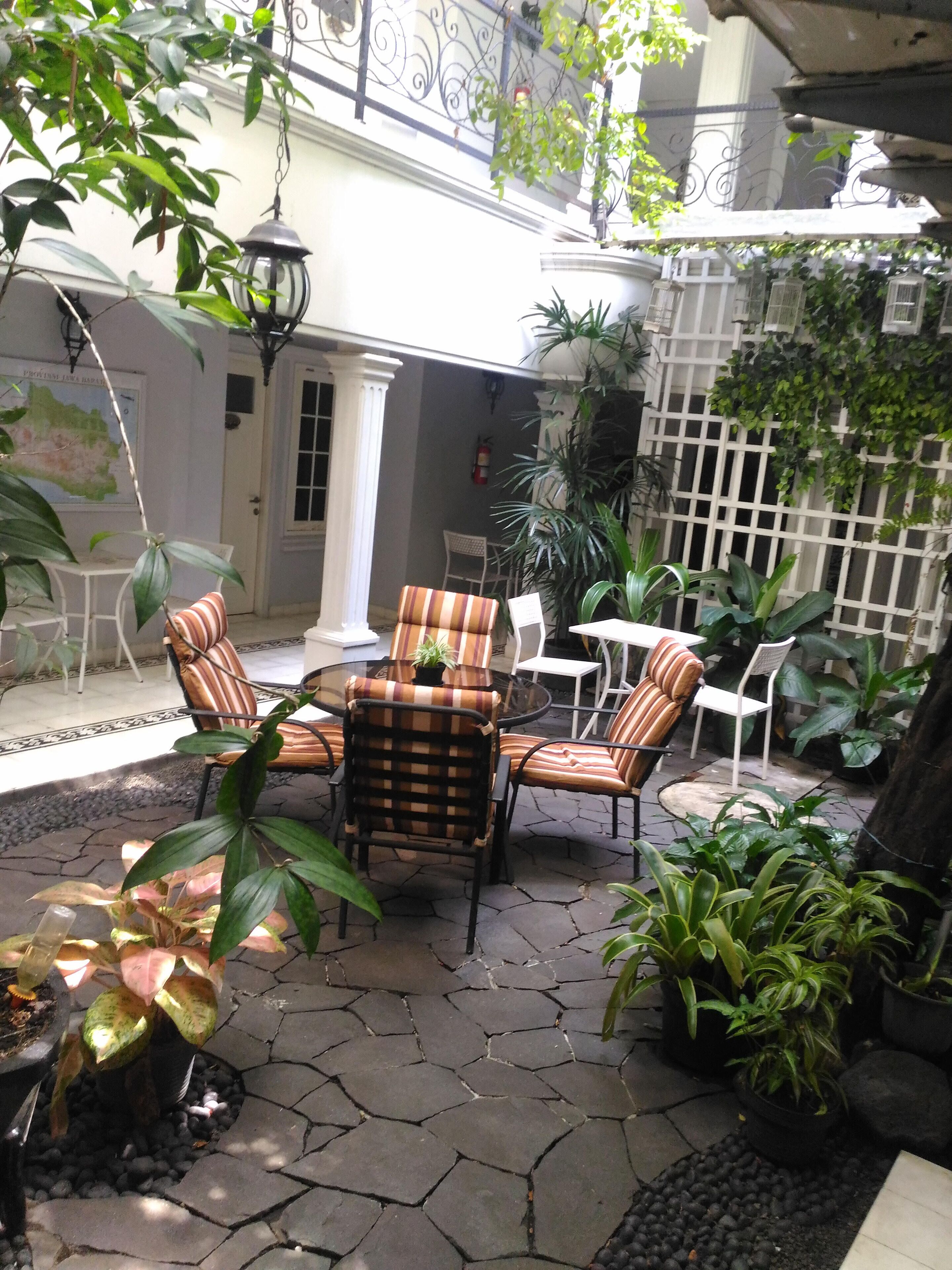 A patio area with outdoor furniture, potted plants, and a stone floor.