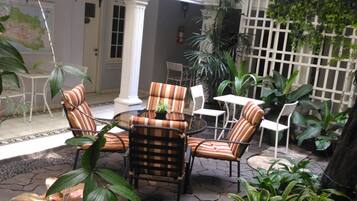 A patio area with outdoor furniture, potted plants, and a stone floor.