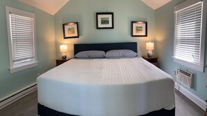 Ein Schlafzimmer mit einem großen Bett, zwei Nachttischlampen und drei gerahmten Bildern an der Wand.