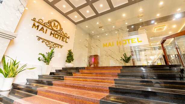 L’entrée d’un hôtel, avec des marches en marbre, une porte en verre et un plafond doté d’un éclairage encastré.