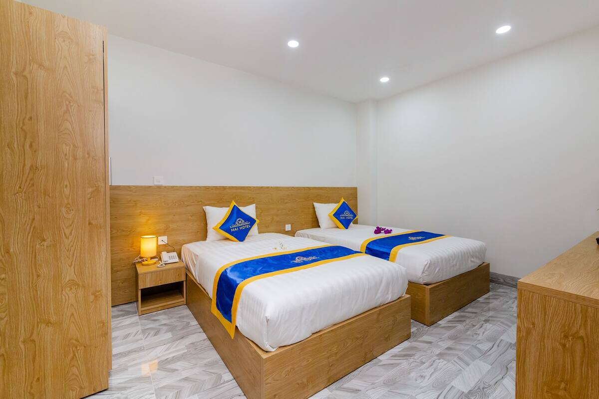 Ein Hotelzimmer mit zwei Betten, einem Holzkopfteil, Nachttischen mit Lampen und einem Holzbüro.
