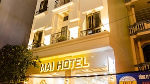 Un hôtel reconnaissable à son enseigne bien visible, doté de nombreux balcons et d’un escalier menant à l’entrée.