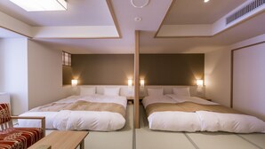 A hotel room with two beds, a wooden bench, and a small table. - Oyado Tsukiyonousagi (Izumo)