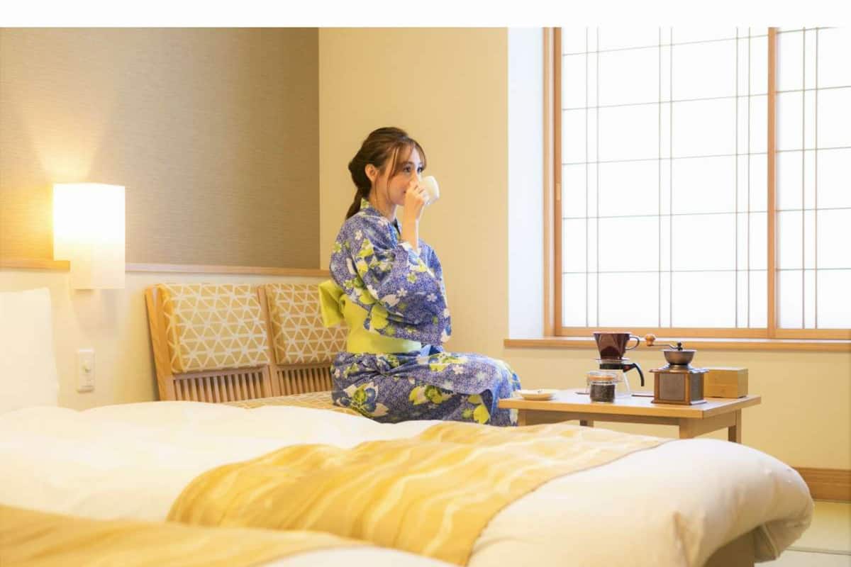 A hotel room with a bed, a bedside table with a coffee maker, and a window with a view.