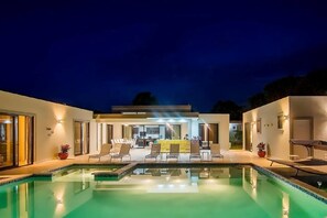 A modern house with a swimming pool, outdoor seating area, and a well-lit interior. - Caribbean Style Getaway (Sosúa)