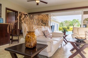 A modern living room with a white sofa, a coffee table, and a vase with dried plants. - Beautifully Italian Designed Villa (Sosúa)