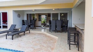 Eine moderne Außenpatio mit Liegestühlen und Barbereich, mit Pool und Blick ins Innere.
