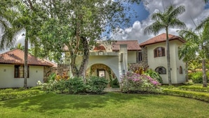 A two-story house with a central archway, surrounded by well-maintained lawns and tropical plants. - Casa Las Brisas A Caribbean Vacation Dream (Cabarete)
