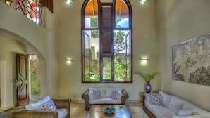 A spacious living area with a high arched window, two sofas, a coffee table, and a painting on the wall. - Casa Las Brisas A Caribbean Vacation Dream (Cabarete)