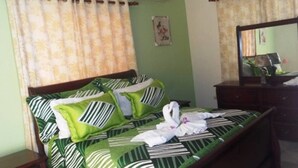 A neatly made bed with green and white striped bedding, a wooden headboard, and a green pillow.