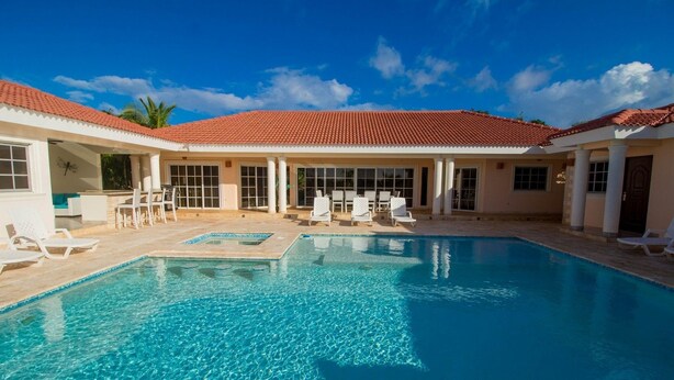 A swimming pool with lounge chairs and a covered seating area.