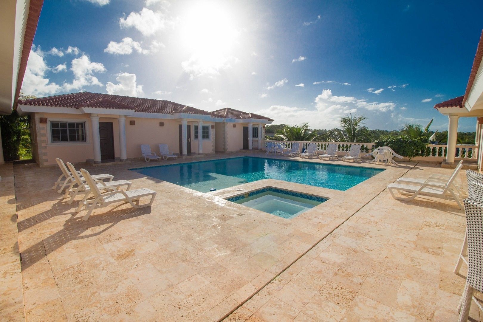 A swimming pool with lounge chairs, a sun terrace, and a view of the surrounding landscape.